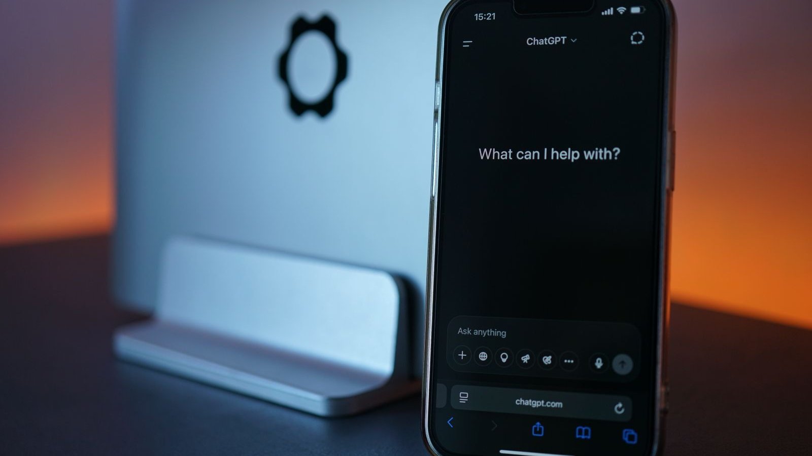 Masada dizüstü bilgisayarın yanında yapay zekâ sohbet ekranı açık akıllı telefon