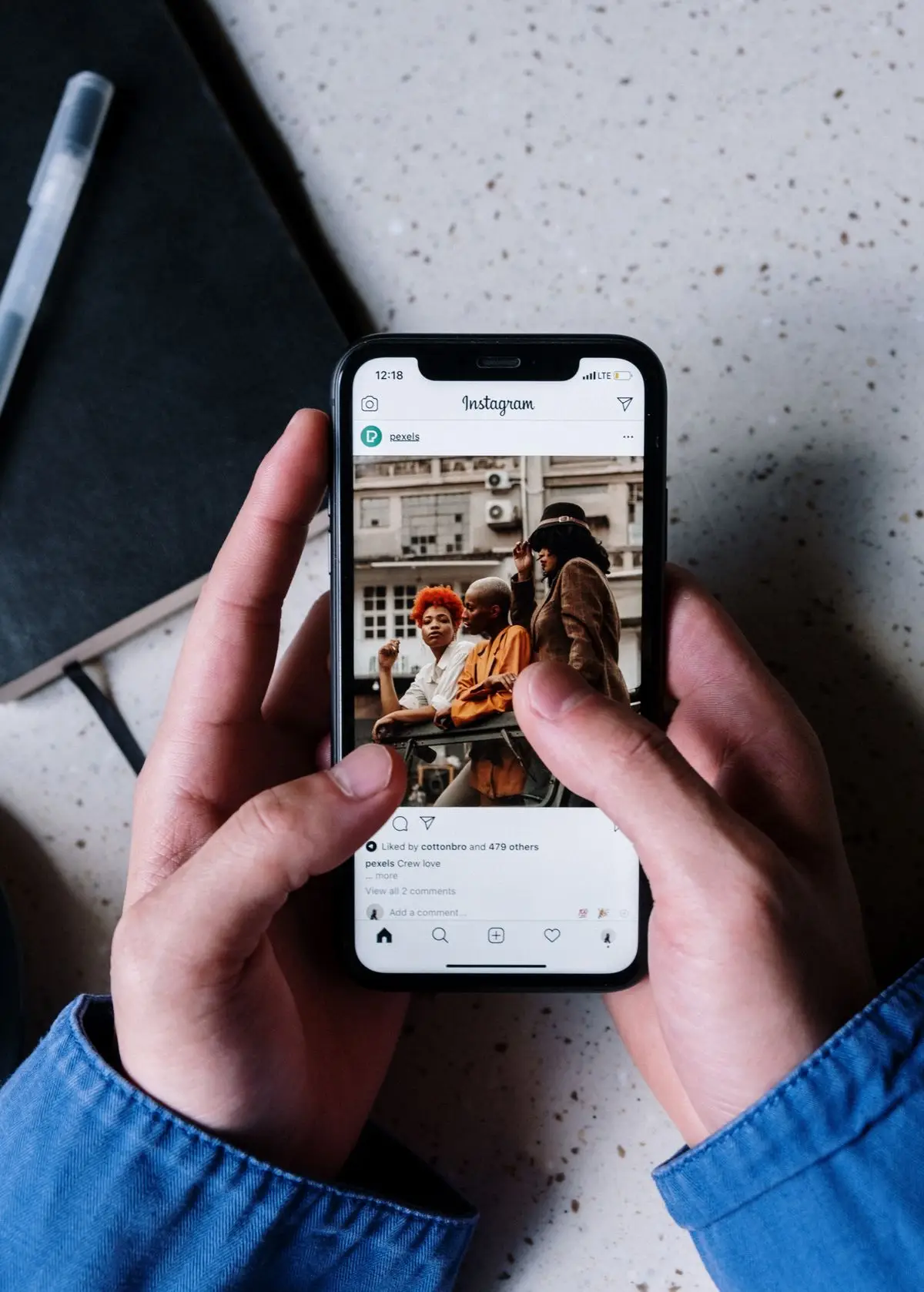 Person browsing content on Instagram, holding a notebook